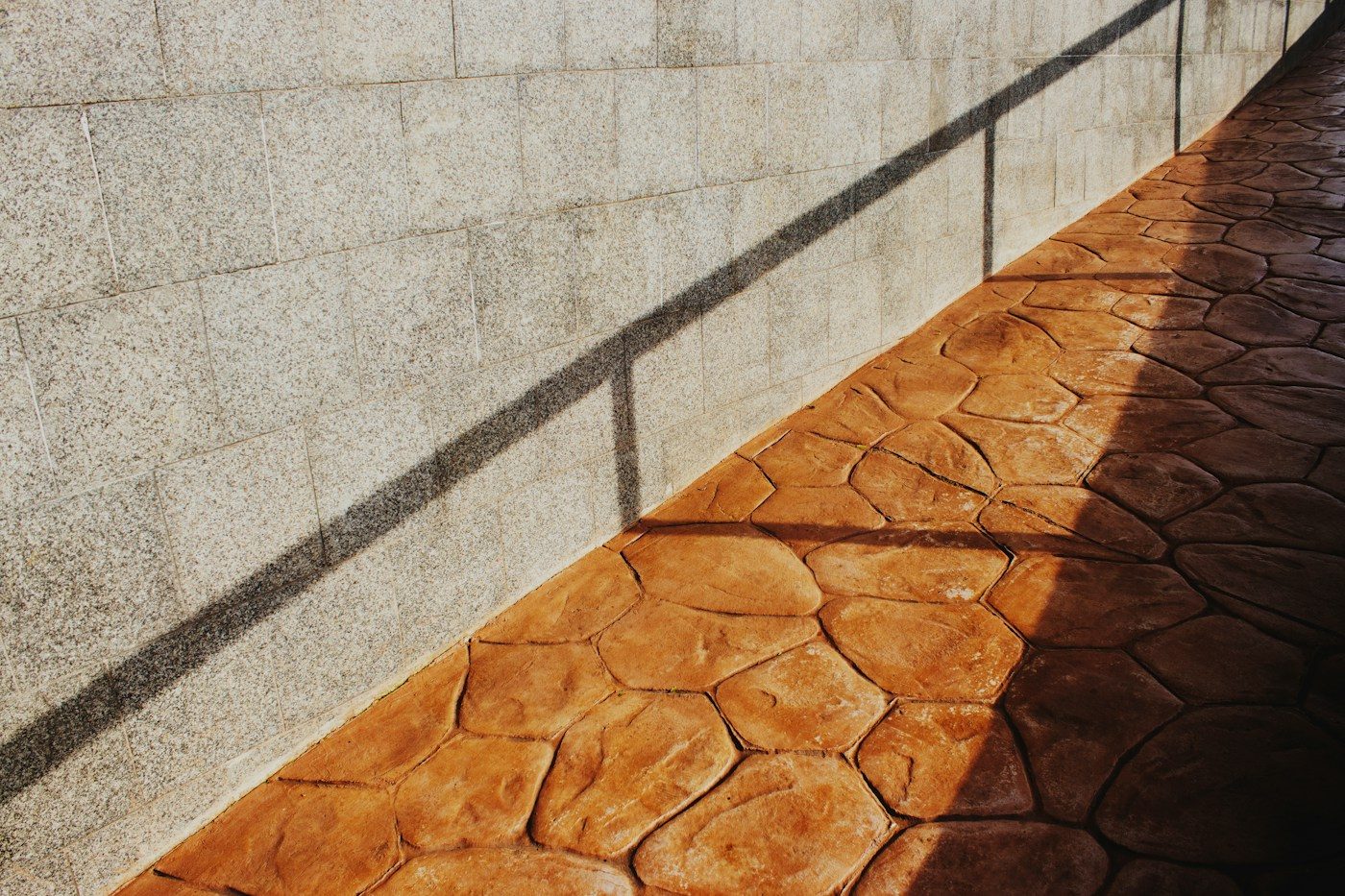 Terracotta-coloured stamped concrete walkway beside a wall